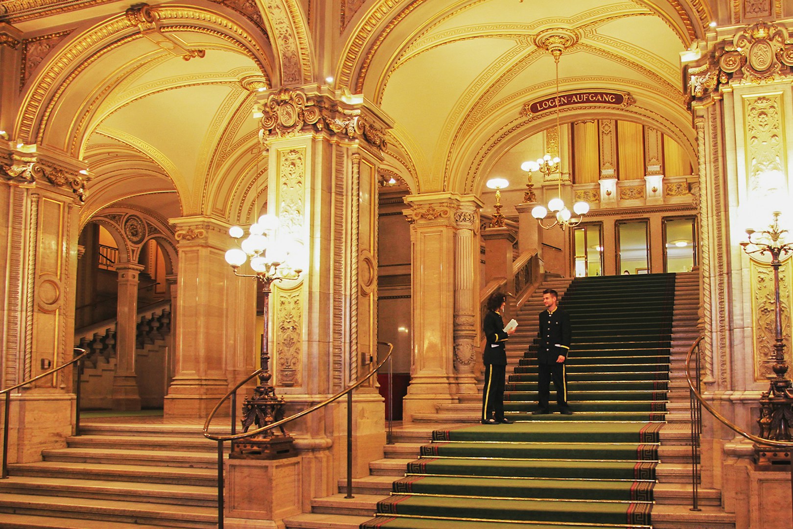 Vienna State Opera grand staircase with ornate arches and staff in formal attire.