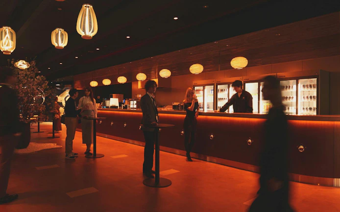 Bar area at DRUM TAO Theater Kyoto with people socializing and staff serving drinks.