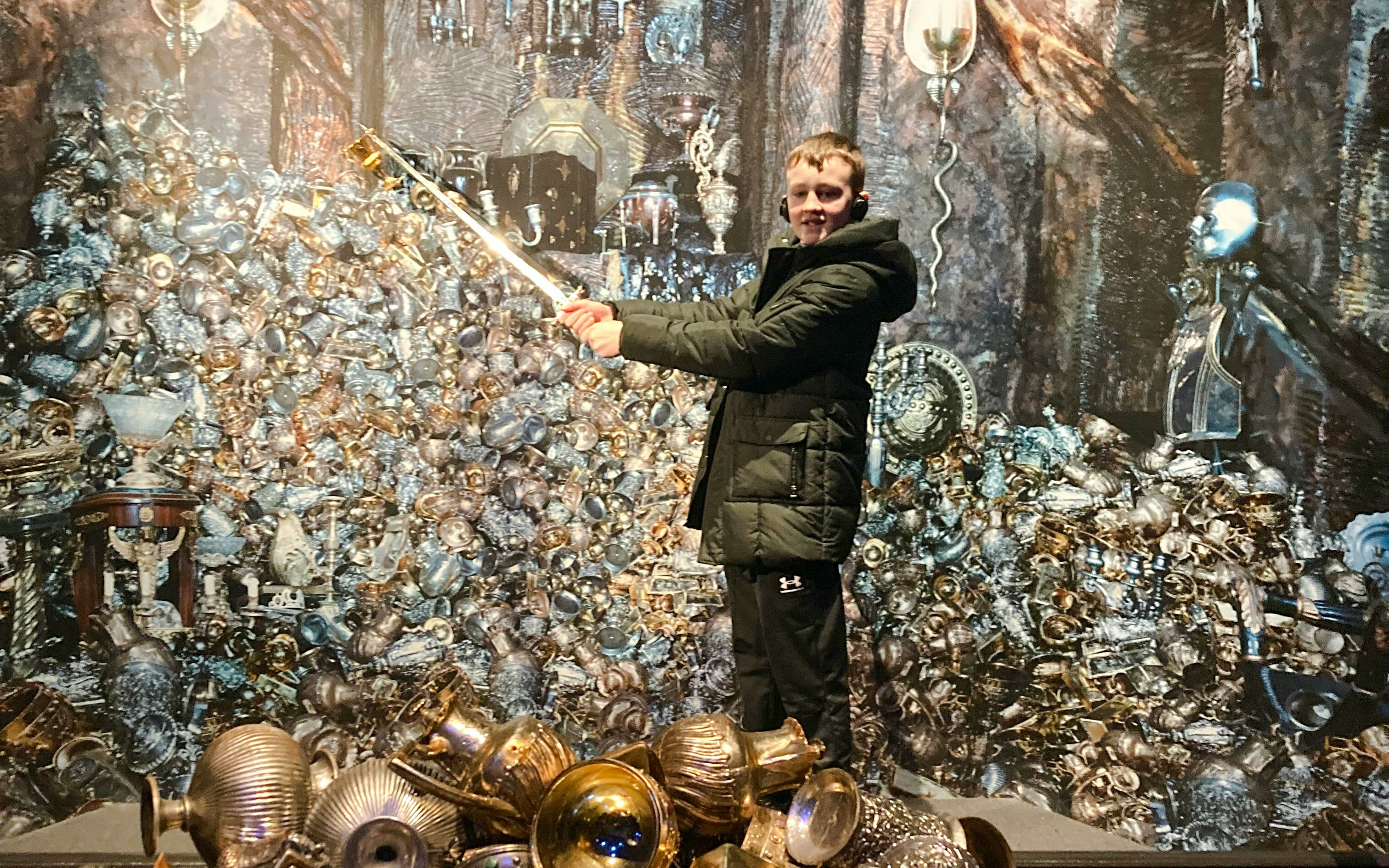Person holding a wand in front of Gringotts Wizarding Bank treasure pile, Harry Potter tour.