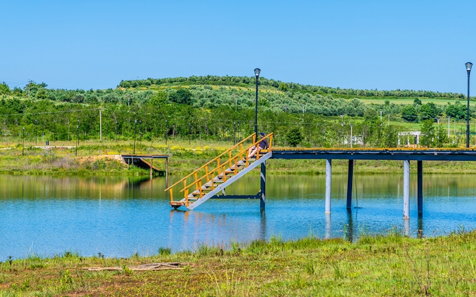 Staircase leading to a pier over the lake at Belsh lakes, surrounded by greenery.