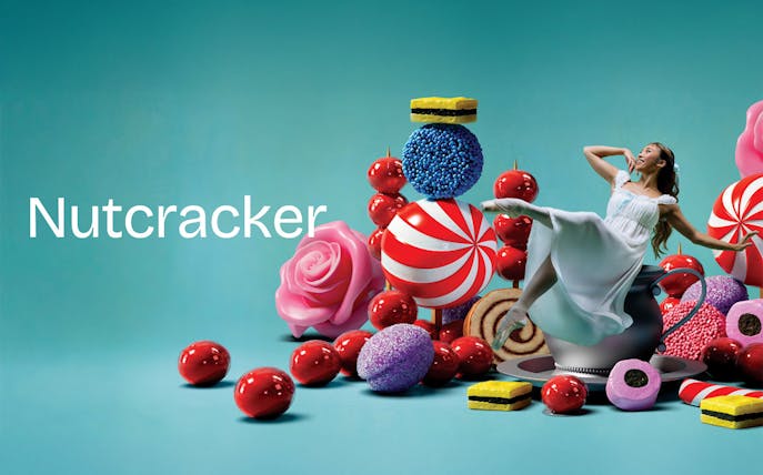 Ballerina dancing among oversized sweets for Nutcracker West End show.