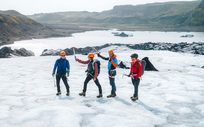 Guests hiking on Solheimajökill Glacier with ice axes and helmets in Iceland.