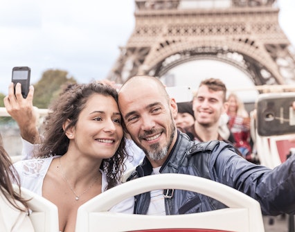 Tourists taking selfies on a bus with the Eiffel Tower in the background, Paris.