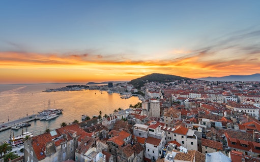 Sunset view of Split Riviera with boats docked, highlighting the coastal cityscape.