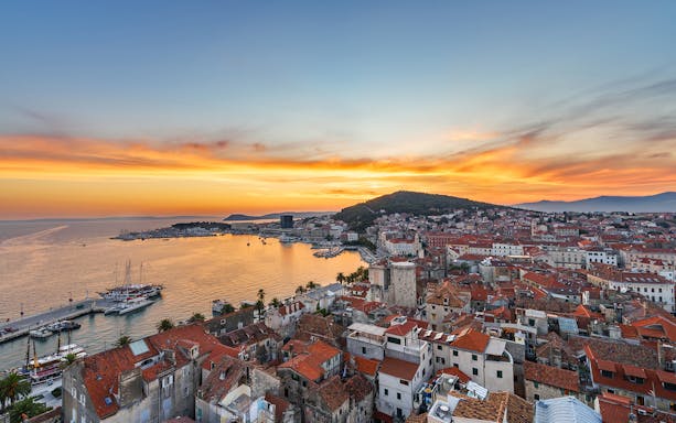 Sunset view of Split Riviera with boats docked, highlighting the coastal cityscape.