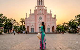 Woman in traditional dress at Da Nang Cathedral during sunset.