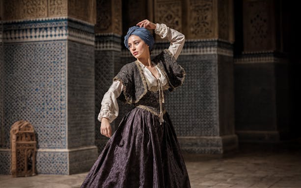 Female performer in 16th-century Spanish attire at Alcazar of Seville night tour.