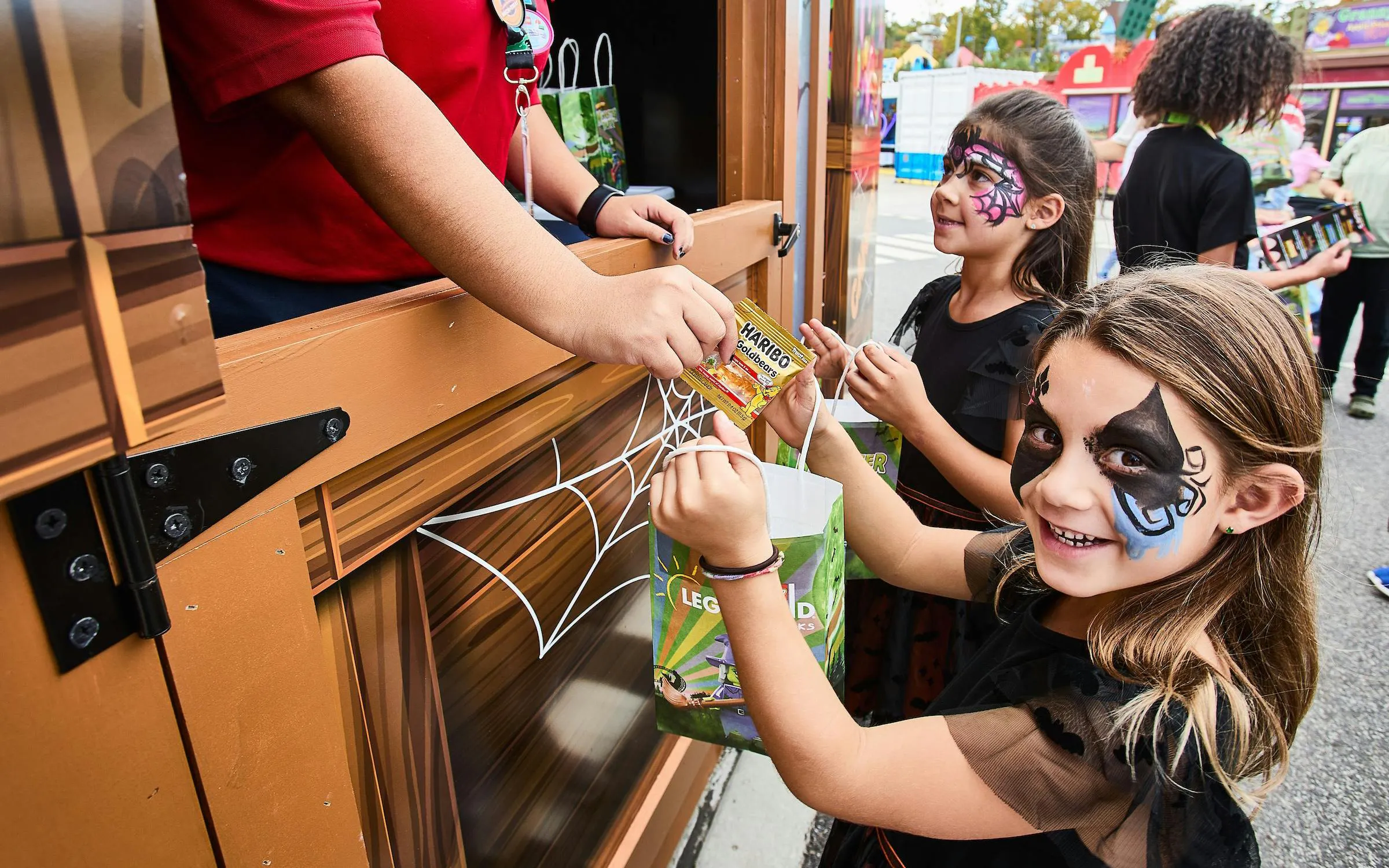 Children in face paint receiving candy at Legoland New York Halloween event.