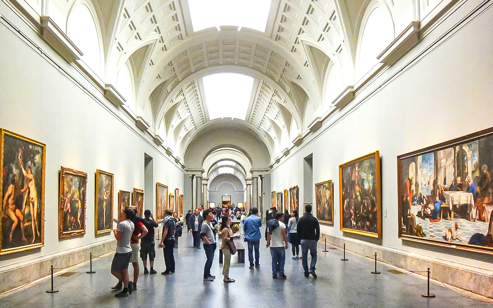 Visitors exploring art in a gallery at Prado Museum, Madrid.
