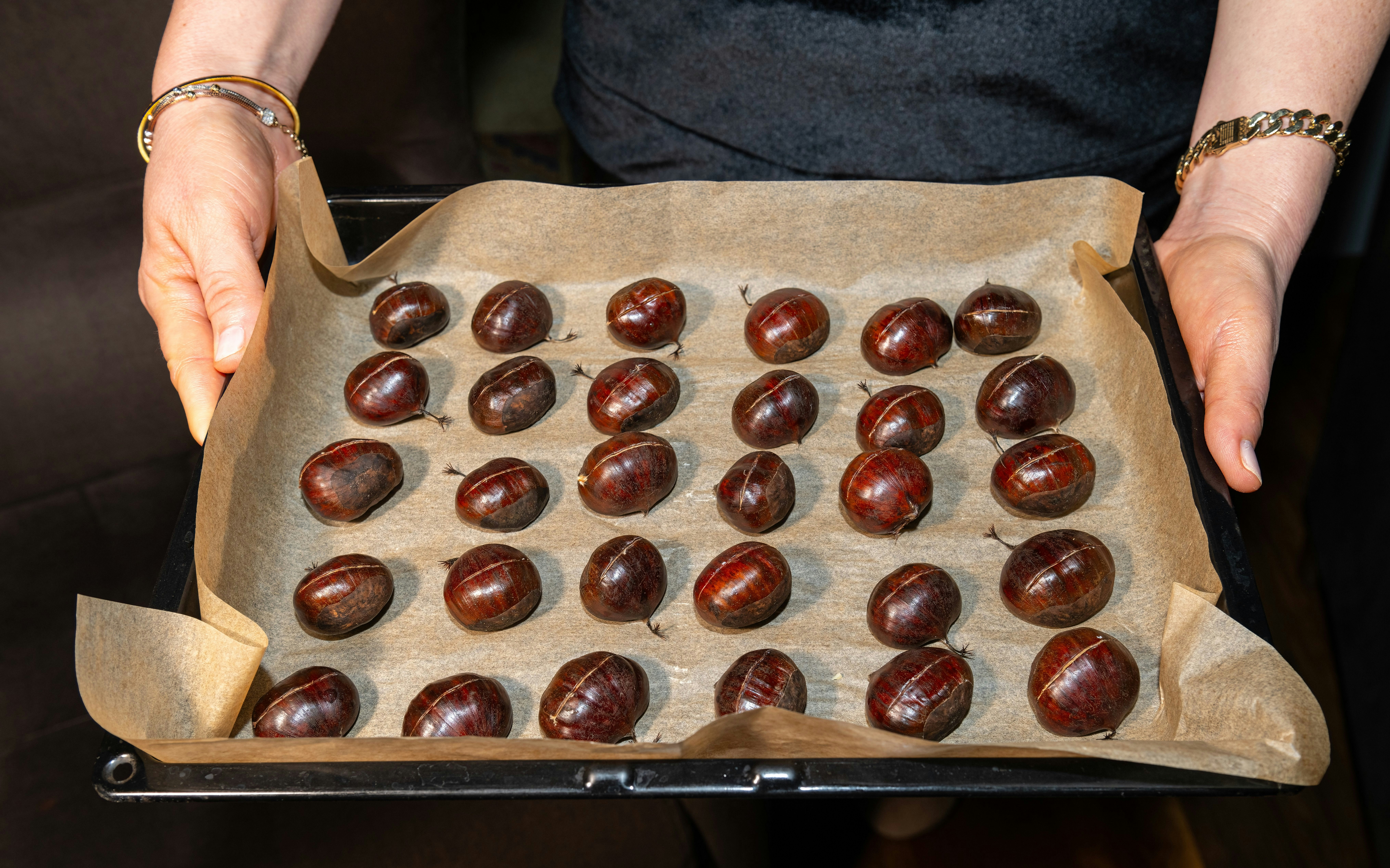 Chestnuts scored on top, arranged on a baking sheet for roasting.