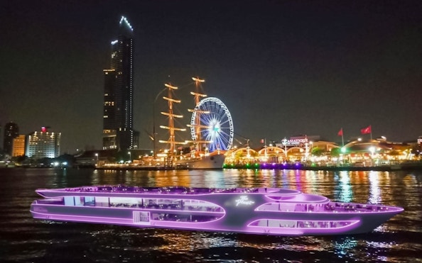Dinner cruise ship at Asiatique Pier with Bangkok skyline and Ferris wheel.