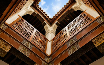 Bahia Palace courtyard with intricate wooden carvings and open sky in Marrakech.