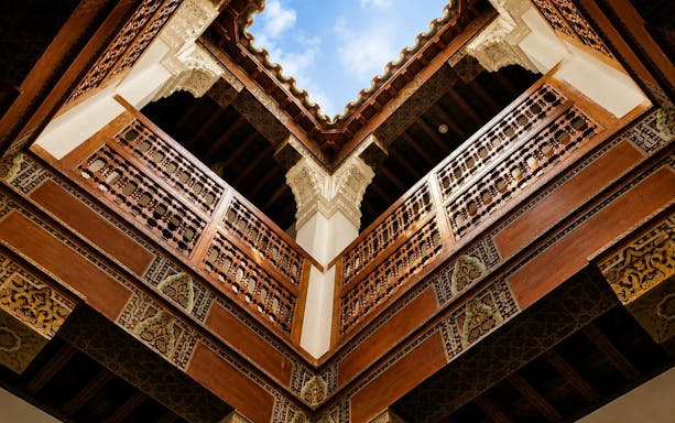 Bahia Palace courtyard with intricate wooden carvings and open sky in Marrakech.