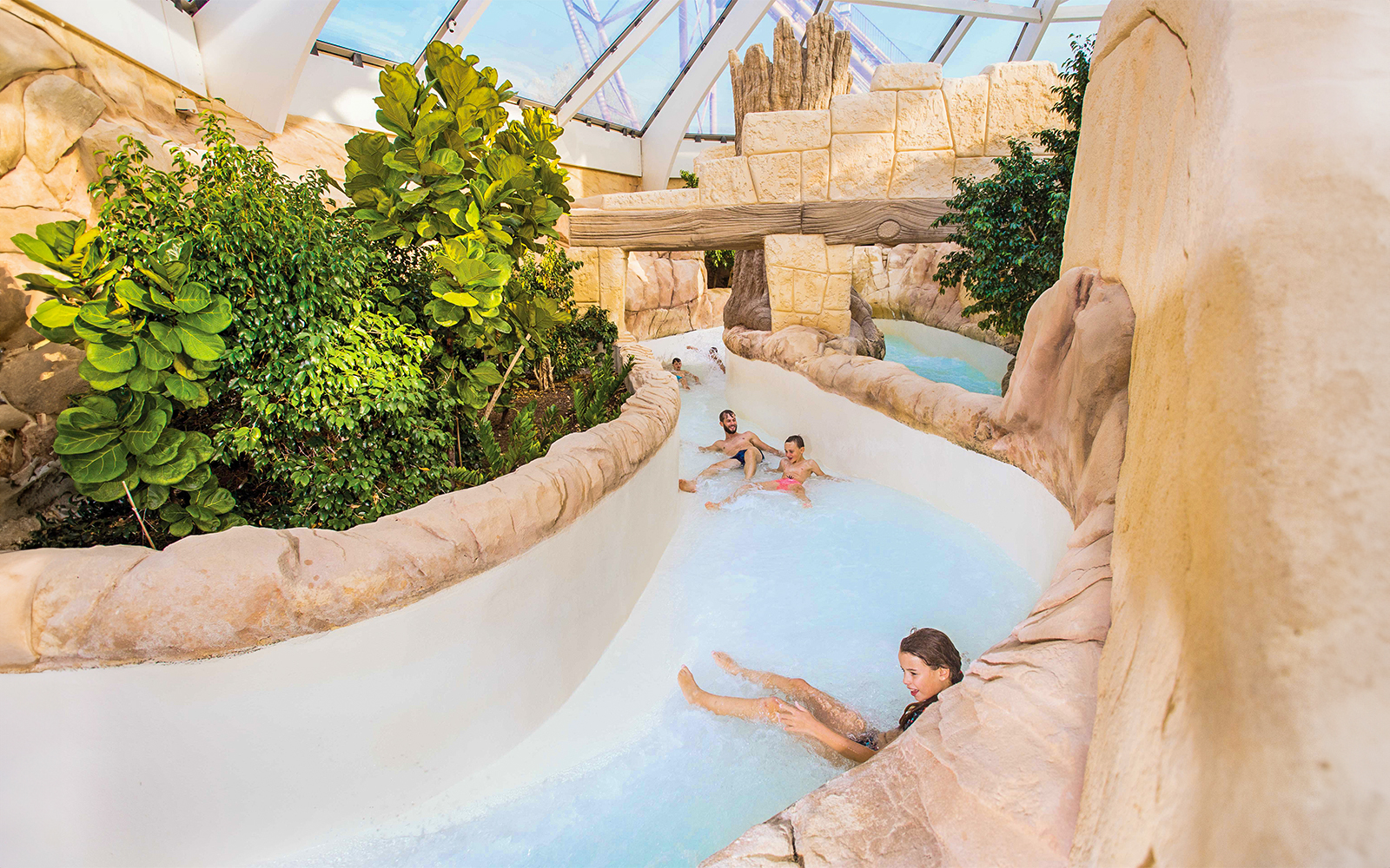Tourists sliding down the Rapido slide at Aqualibi, surrounded by lush greenery.