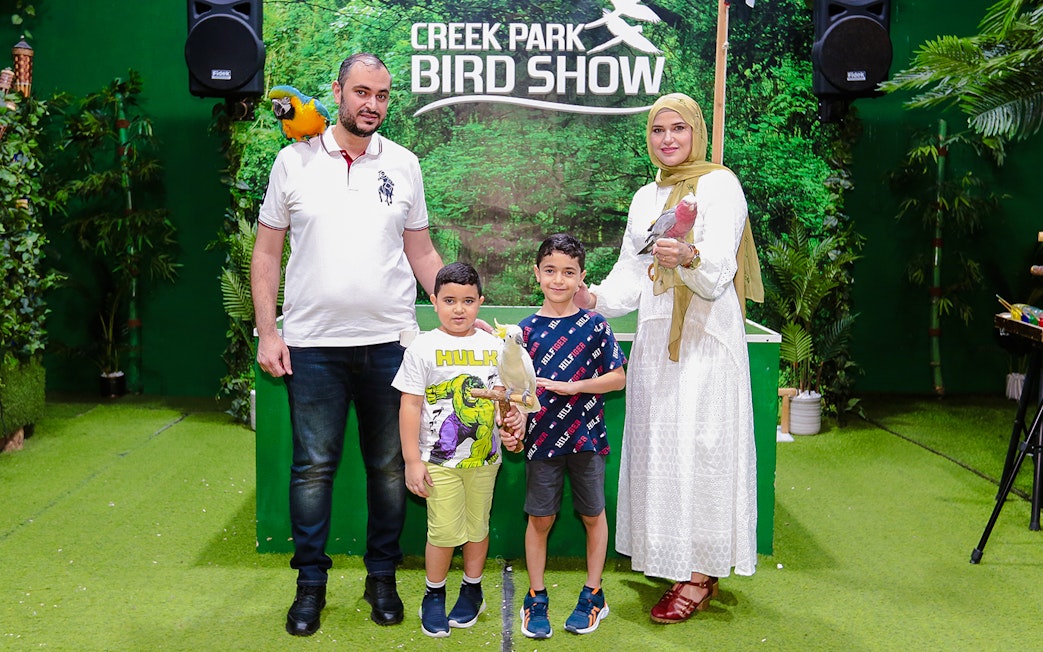 Family posing with parrots at Creek Park Bird Show.