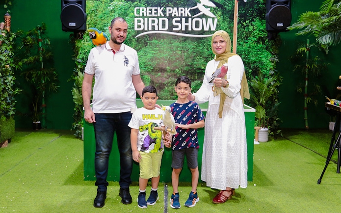 Family posing with parrots at Creek Park Bird Show.