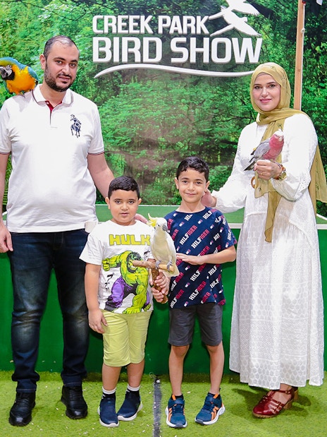Family posing with parrots at Creek Park Bird Show.