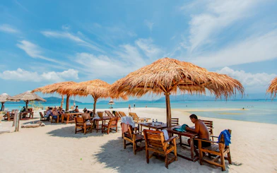Beach shacks with thatched roofs on Koh Samui's Pig Island, overlooking the ocean.