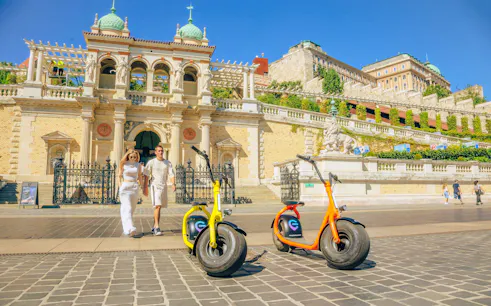 E-scooters parked in front of Budapest Castle District with tourists walking nearby.