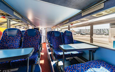 Interior seating of Autostradale Airport Transfer bus with tables and blue seats.