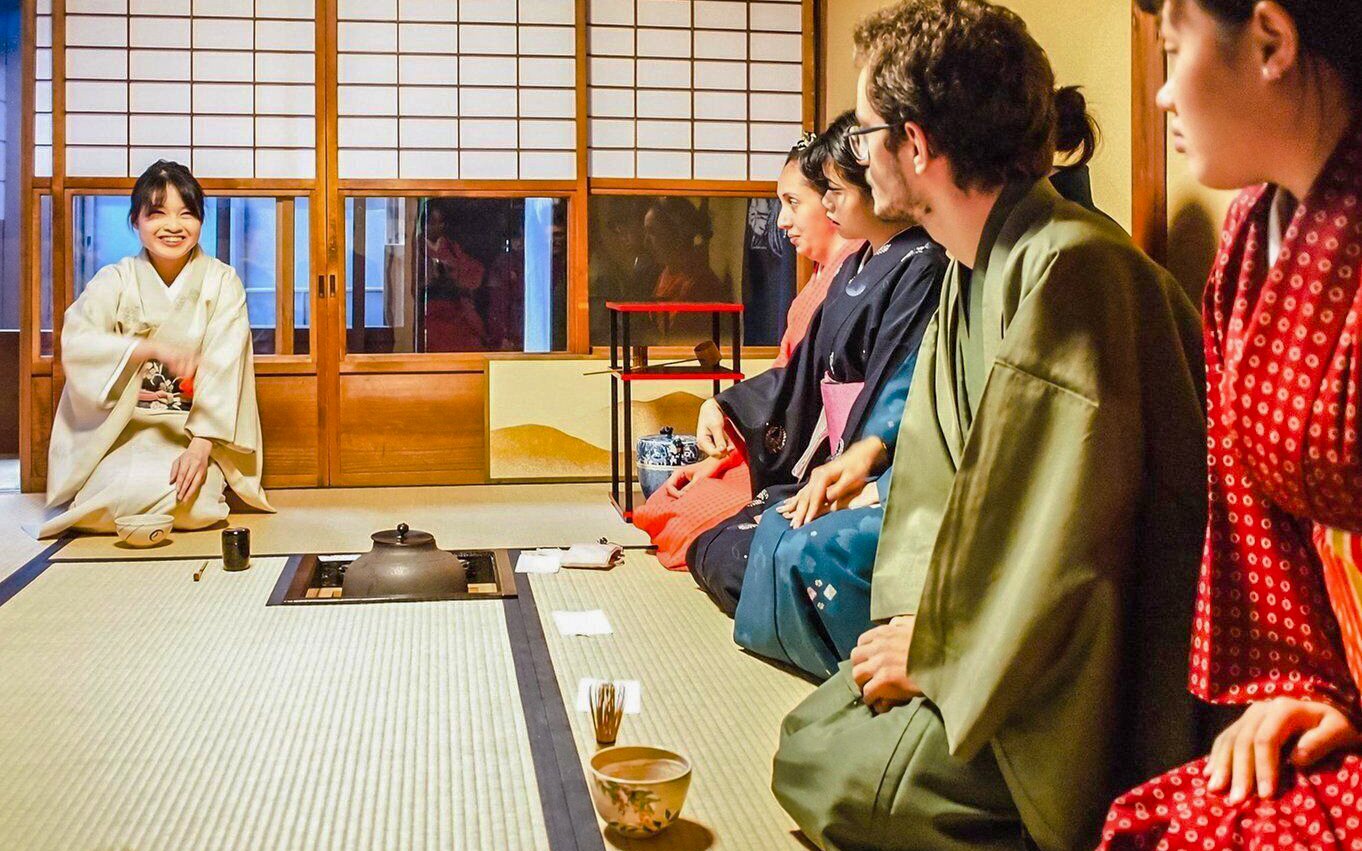 Participants in traditional attire at a Japanese tea ceremony, learning matcha-making techniques.
