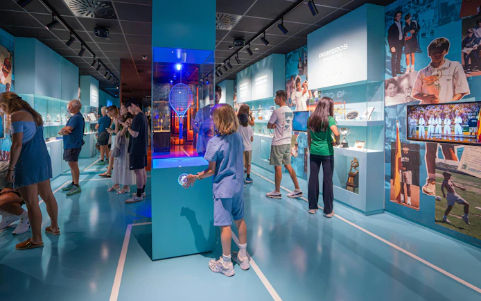 Visitors exploring exhibits at Rafa Nadal Museum, featuring tennis memorabilia and interactive displays.