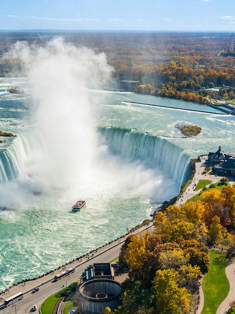 Niagara Falls view from Canada side with boat in misty water flow.