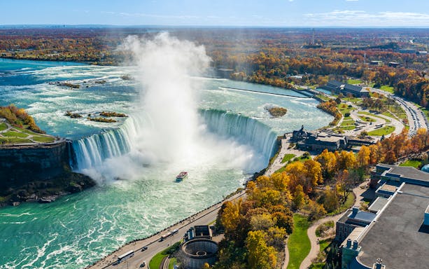 Niagara Falls view from Canada side with boat in misty water flow.