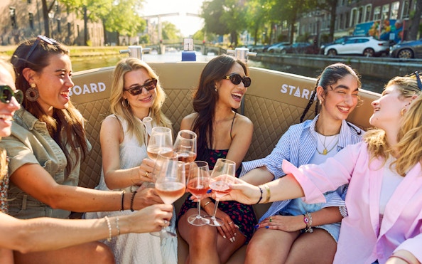 Friends enjoying drinks on a canal cruise in Amsterdam's Red Light District.