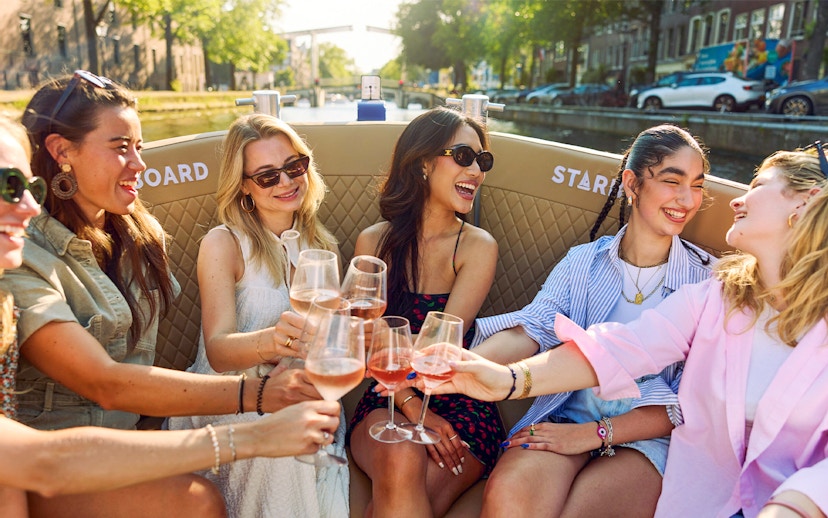 Friends enjoying drinks on a canal cruise in Amsterdam's Red Light District.