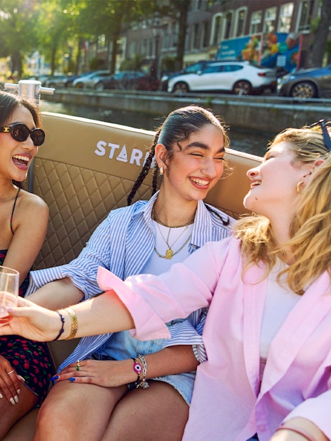 Friends enjoying drinks on a canal cruise in Amsterdam's Red Light District.