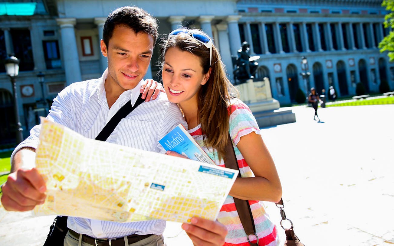 Couple exploring map outside Prado Museum, Madrid.