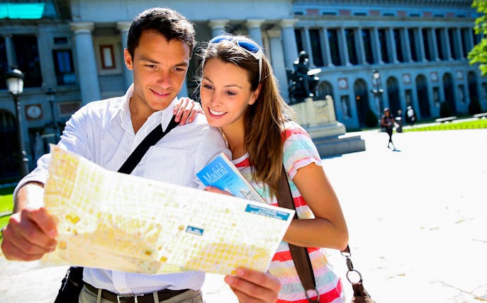 Couple exploring map outside Prado Museum, Madrid.