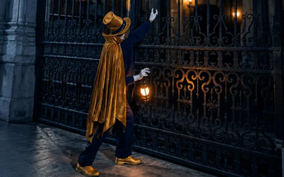 Tour guide in costume holding lantern during theatrical tour of Madrid.