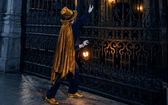 Tour guide in costume holding lantern during theatrical tour of Madrid.