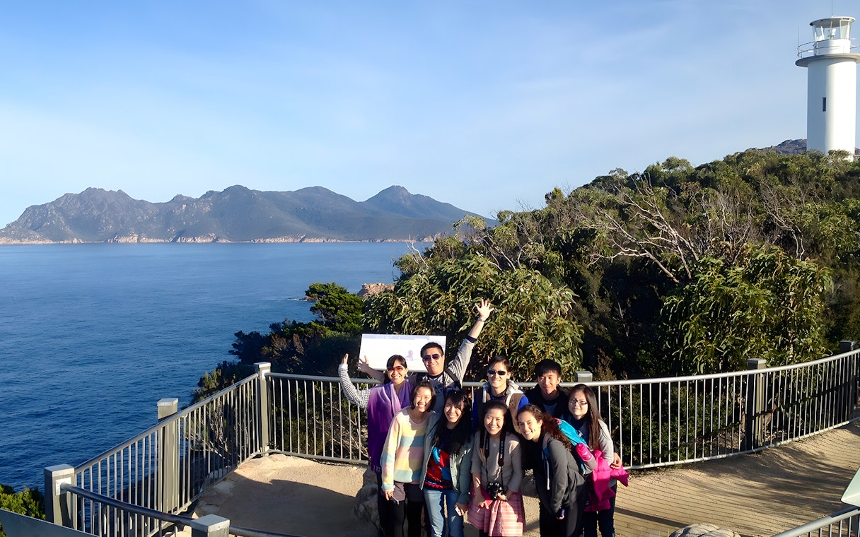 Group at Wineglass Bay lookout with ocean and mountains, Launceston to Hobart tour.