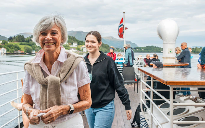 Tourists enjoying the Ålesund-Geiranger-Ålesund Fjord boat tour with scenic views.