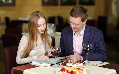 Couple reviewing menu on a cruise dining table with wine and dessert.