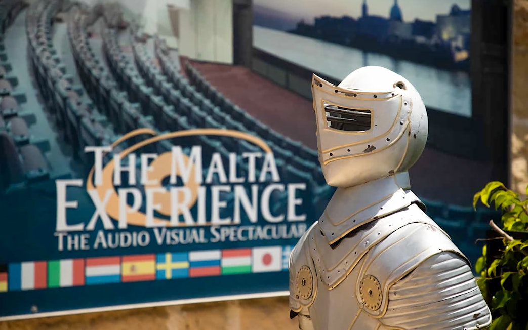 Knight armor statue in front of The Malta Experience sign, Valletta.
