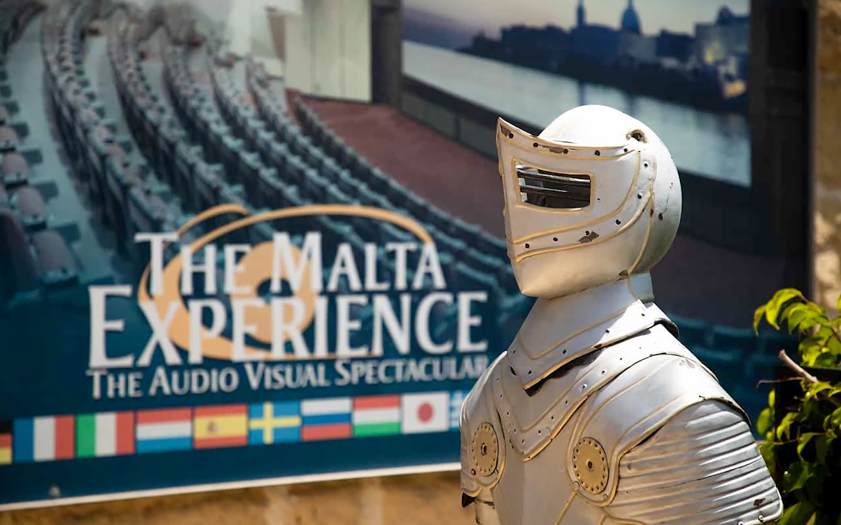 Knight armor statue in front of The Malta Experience sign, Valletta.