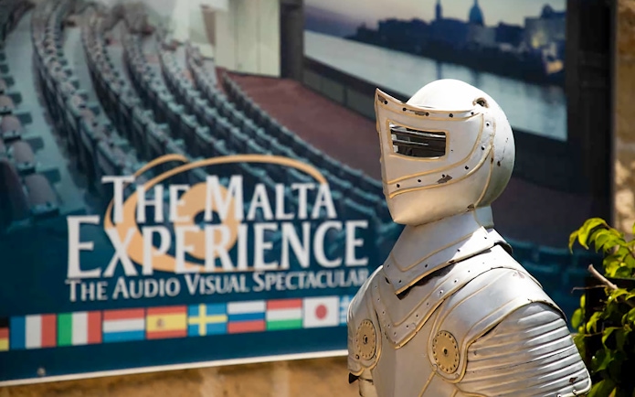 Knight armor statue in front of The Malta Experience sign, Valletta.