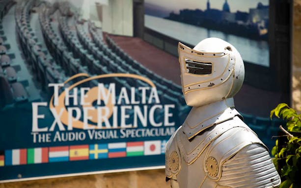 Knight armor statue in front of The Malta Experience sign, Valletta.