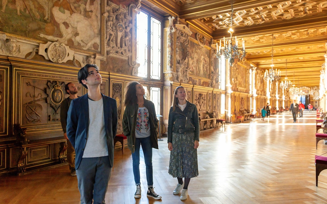 Visitors exploring ornate hall at Vaux-le-Vicomte during Paris audio-guided tour.