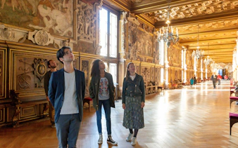 Visitors exploring ornate hall at Vaux-le-Vicomte during Paris audio-guided tour.