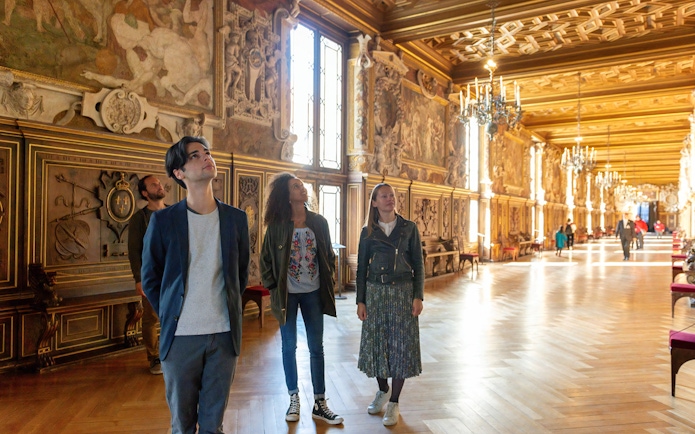 Visitors exploring ornate hall at Vaux-le-Vicomte during Paris audio-guided tour.