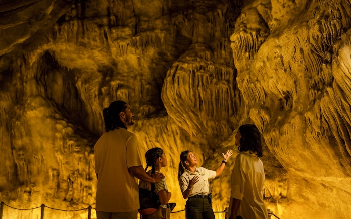 Guide explaining scalloping wall formations at Rainforest Wild Adventure cave tour.
