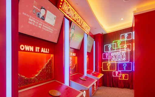 Interactive exhibit at MONOPOLY DREAMS™️ Hong Kong with neon signs and game stations.
