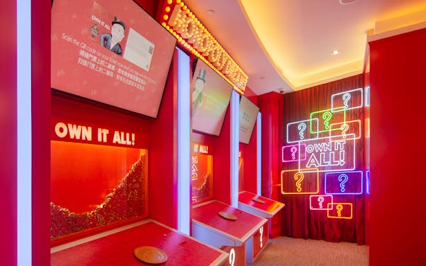 Interactive exhibit at MONOPOLY DREAMS™️ Hong Kong with neon signs and game stations.