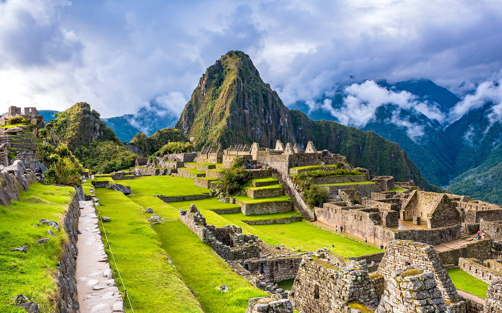 Machu Picchu ruins with terraces and Huayna Picchu mountain in the background.