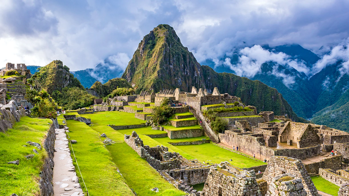 Machu Picchu ruins with terraces and Huayna Picchu mountain in the background.